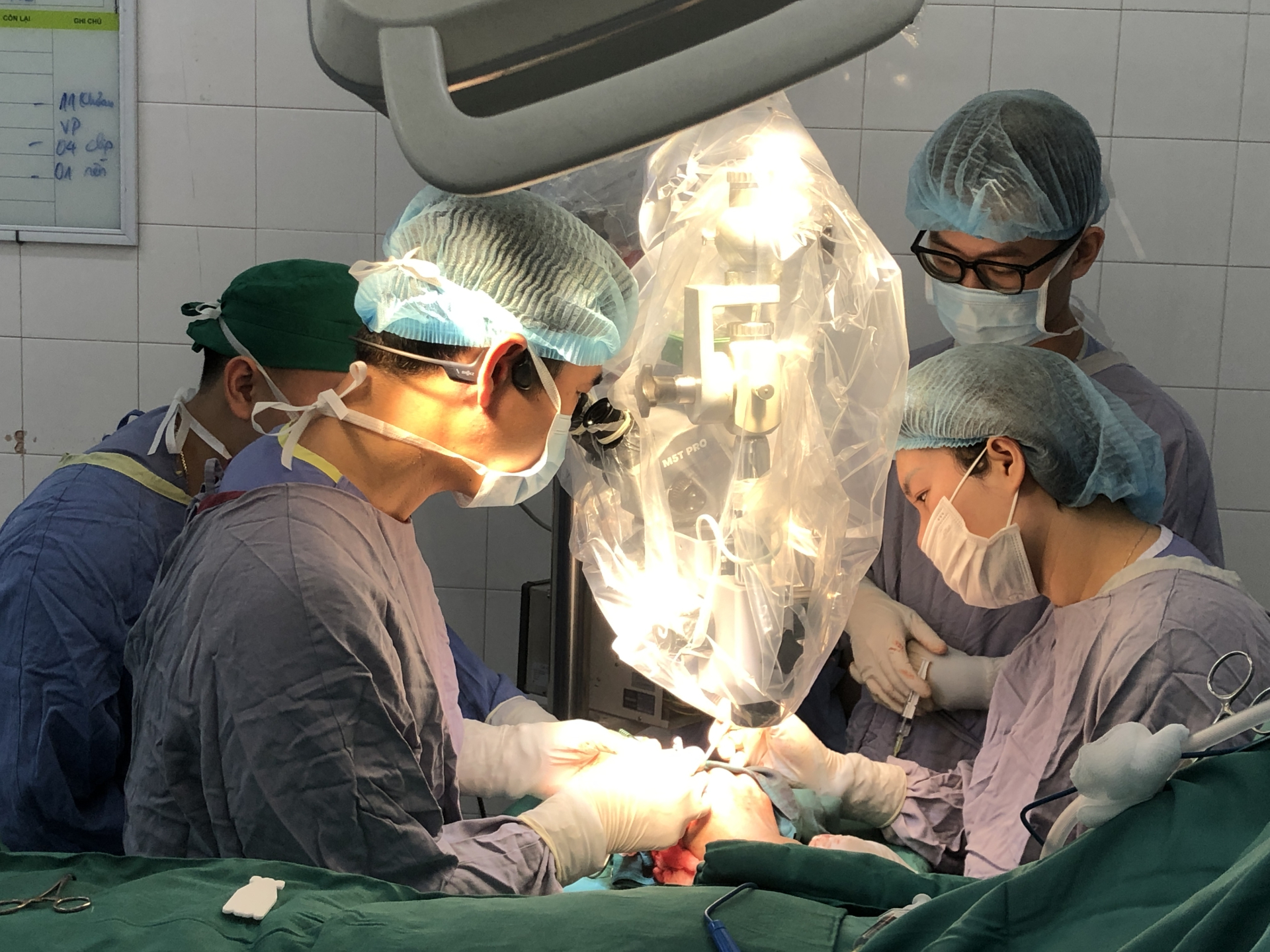 Ê-kíp mổ thực hiện vi phẫu nối lại ngón tay cho người bệnh với kính hiển vi