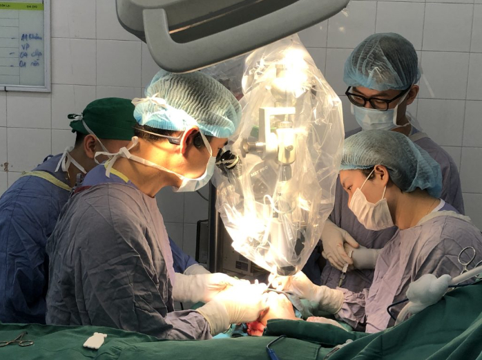 Ê-kíp mổ thực hiện vi phẫu nối lại ngón tay cho người bệnh với kính hiển vi