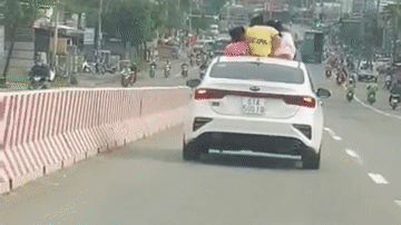 Xe hơi 4 chỗ chở 3 đứa trẻ trên nóc