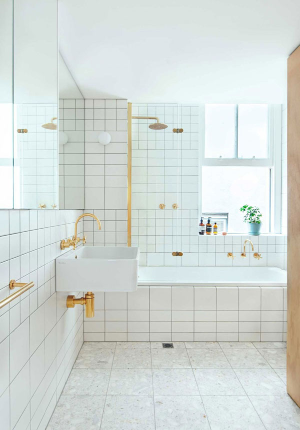   Phòng tắm được trang trí với sàn và tường ốp gạch đá màu trắng thông thường nhưng gắn kết bằng một cách sáng tạo, lạ mắt.  Vòi nước và tất cả các phụ kiện kim loại được mạ màu vàng đem lại sự sang trọng cho toàn bộ phòng tắm.  