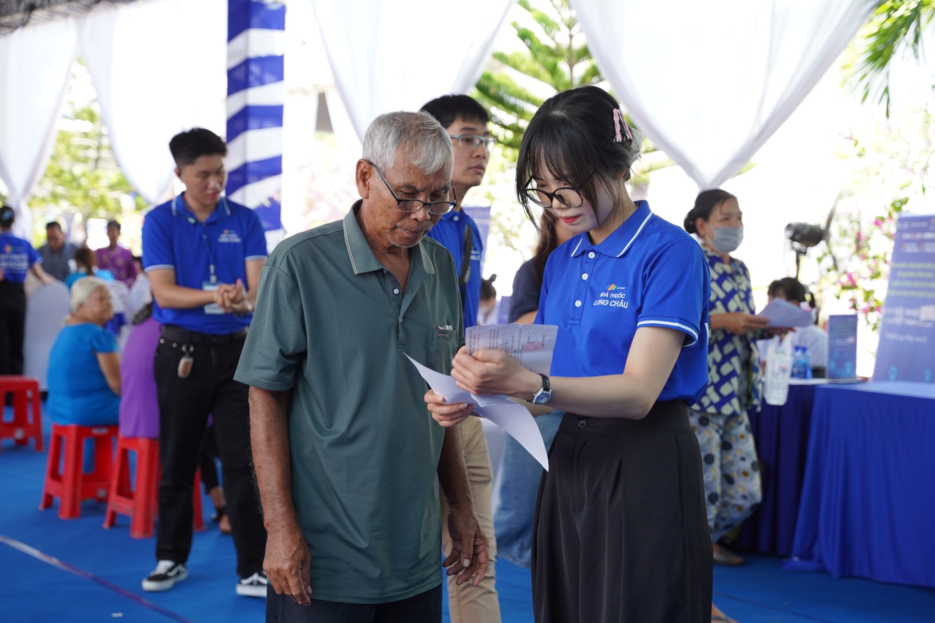 Nhân viên Long Châu tận tình hướng dẫn người cao tuổi trong ngày hội khám và phát thuốc miễn phí.