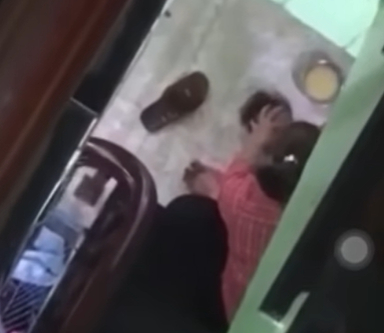 Trẻ bị đè dưới sàn nhà, bị đánh liên tục vào đầu để ép ăn. (Ảnh cắt từ clip)              Ảnh cắt từ clip        