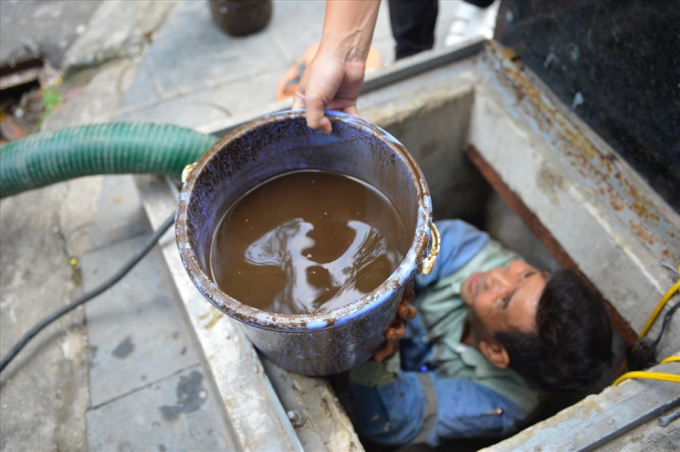 Những xô nước chứa đầy váng dầu, cặn đặc sệt, bốc mùi được đưa ra ngoài bể trong quá trình thau rửa bể tại Golden Land Building. (Nguồn: laodong.vn)