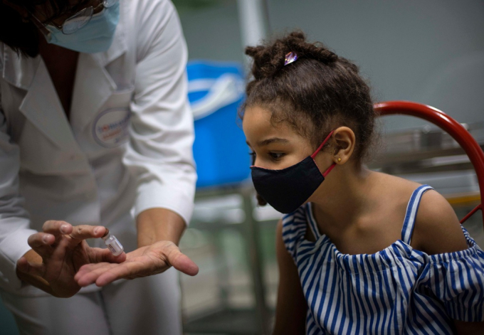 Một trẻ em ở Cuba được nhân viên y tế giới thiệu loại vaccine Covid-19 trước khi tiêm. Ảnh: CNN