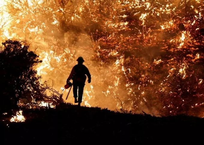 Hình ảnh một nhân viên cứu hỏa đối diện với đám cháy Caldor ở bang California, Mỹ hồi tháng 8/2021. Trong năm 2021, Mỹ ghi nhận 54.350 vụ cháy rừng khiến hơn 2,8 ha rừng bị thiêu rụi. Trong đó, California là một trong những bang bị ảnh hưởng nặng nề nhất.  Tính đến cuối tháng 11 California ghi nhận khoảng 8.600 đám cháy. Ảnh: Reuters