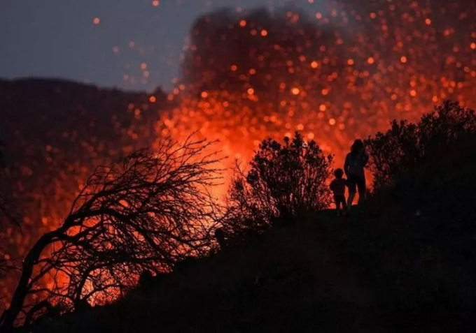 Bức ảnh chụp một phụ nữ và một đứa trẻ trên sườn núi Cumbre Vieja, đảo La Palma (thuộc quần đảo Canary, Tây Ban Nha) hồi tháng 10/2021. Trong đợt phun trào lần này, núi lửa Cumbre Vieja đã hoạt động mạnh mẽ suốt 85 ngày, phá hủy gần 3.000 ngôi nhà và buộc hàng nghìn người phải sơ tán khẩn cấp. Ảnh: Reuters
