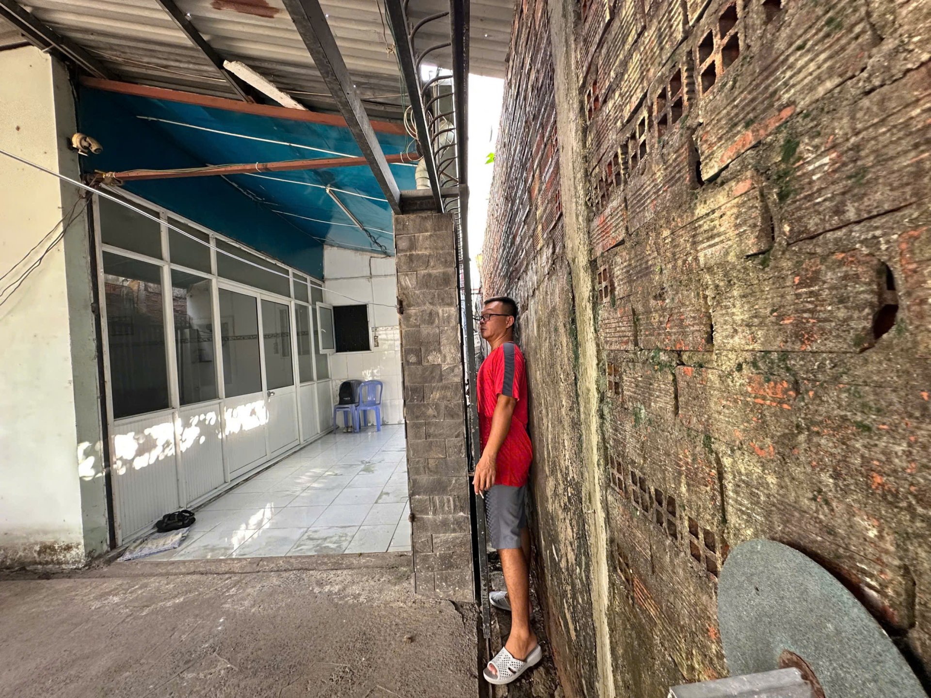 Hằng ngày người dân phải len lỏi qua khe hẹp giữa các bức tường, đây là lối vào nhà duy nhất còn sót lại mà một người trưởng thành cũng khó lòng đi lọt. Ảnh: Tiểu Thúy