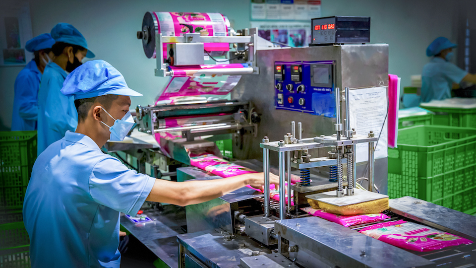 Công nhân vận hành máy đóng gói bao bì bánh tráng tự động