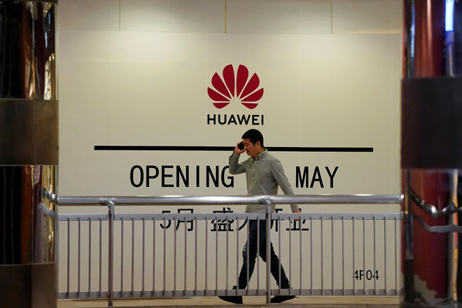 Một người đàn ông đi qua phía trước cửa hàng Huawei tại Thượng Hải. Ảnh: Reuters.