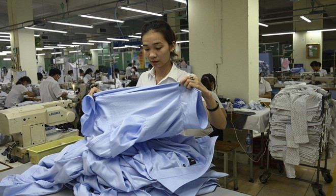 Một công nhân đang gấp áo sơ mi trong xưởng dệt may tại Hà Nội. Ảnh: AFP.