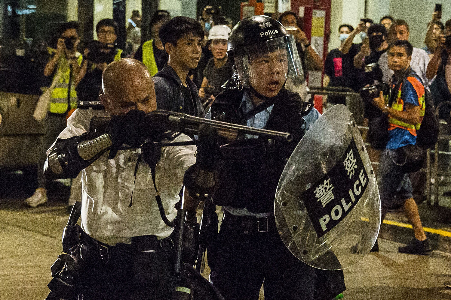 Một sĩ quan cảnh sát chĩa súng trong cuộc đụng độ với những người biểu tình đã tập trung bên ngoài đồn cảnh sát Kwai Chung để hỗ trợ những người biểu tình bị giam giữ và buộc tội bạo loạn ở Hồng Kông vào ngày 30/7.