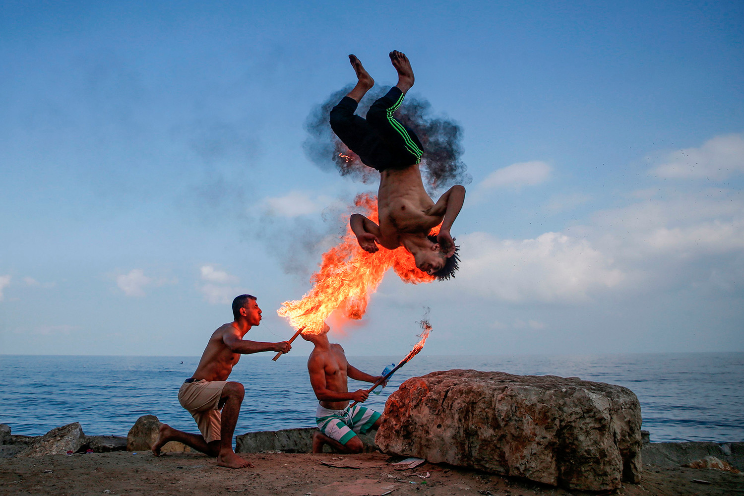 Đàn ông Palestine thực hiện thở lửa trên bãi biển để giải trí cho trẻ em trong kỳ nghỉ hè tại thành phố Gaza vào ngày 1/8.