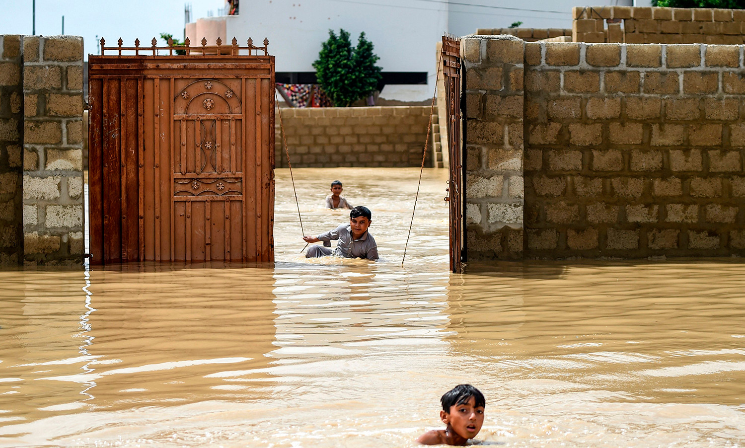Các cậu bé chơi đùa giữa dòng nước lũ trong những cơn mưa gió mùa lớn ở thành phố Karachi, Pakistan, vào ngày 31/7.