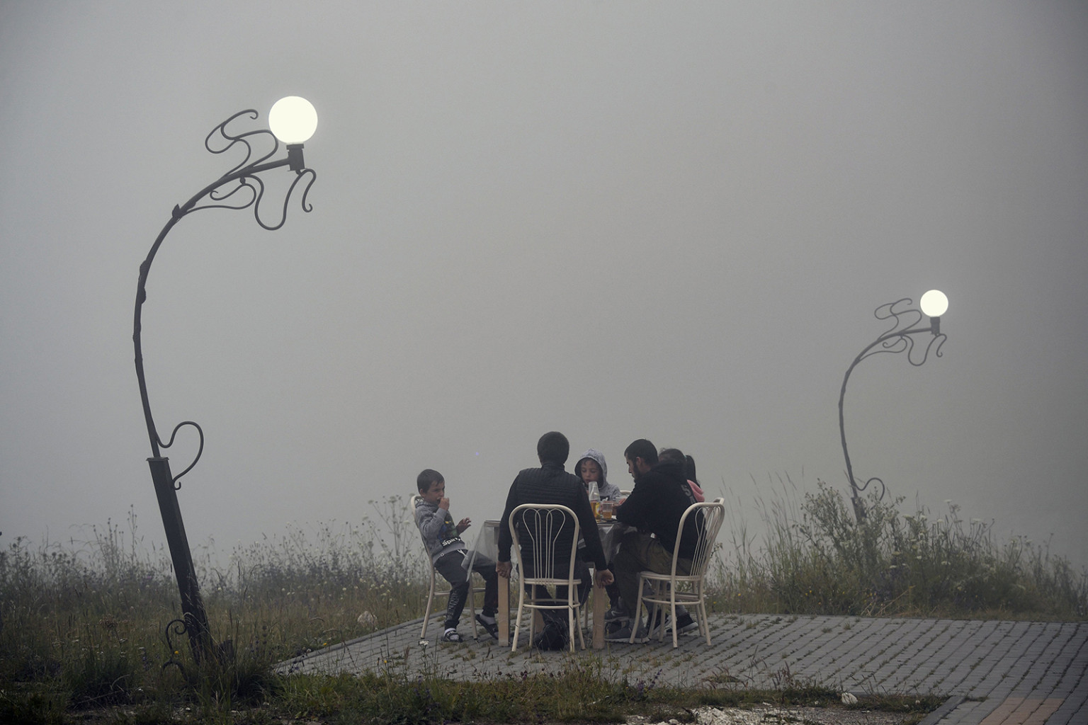   Một gia đình ăn tối bên ngoài trong sương mù tại câu lạc bộ du thuyền Kazenoy ở quận Vedeno của Chechnya vào ngày 24 tháng 7.  
