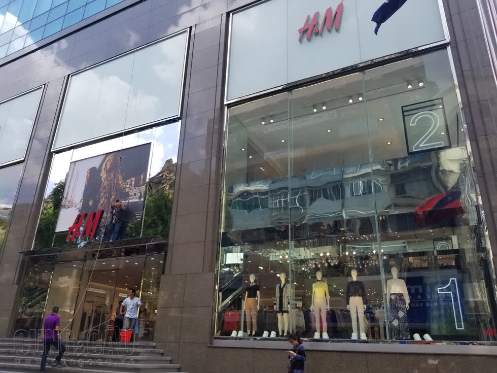 Vài nhân viên đang thay biển quảng cáo trang phục theo xu hướng mới cho cửa hàng H&M- Vincom Đồng Khởi, quận 1.