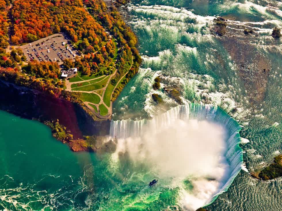   Được hình thành bởi ba thác nước lớn, với 3.160 tấn nước chảy qua thác Niagara mỗi giây, tạo nên một trong những thác nước hùng vĩ nhất thế giới. Màu đỏ và cam của lá cây tương phản với màu xanh lam của dòng nước tạo nên một cảnh tượng ngoạn mục. Thác Niagara vào mùa Thu. Ảnh: Shutterstock SurangaSL  