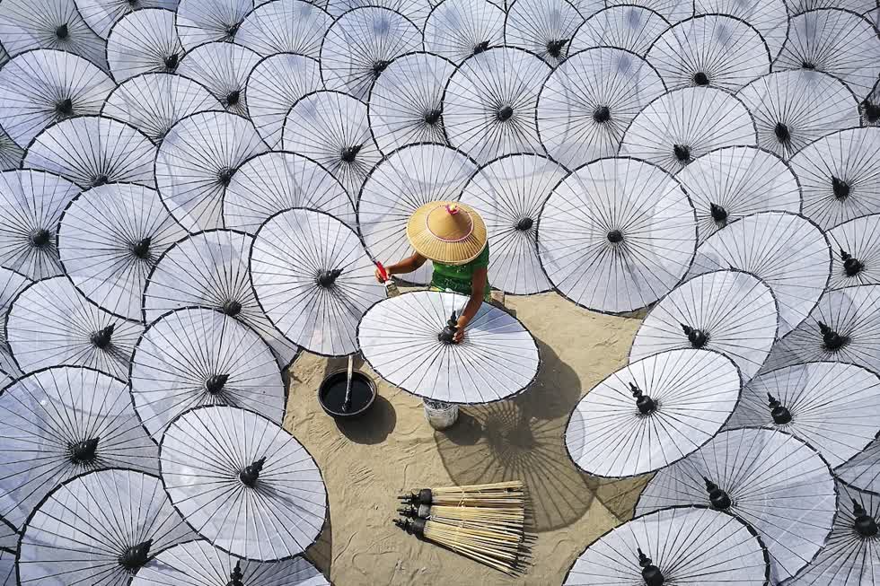 Một người phụ nữ làm những chiếc ô truyền thống tại một nhà máy ở Mandalay, Myanmar. Việc sản xuất một chiếc ô truyền thống không thể được thực hiện bởi một người hoặc trong vòng một ngày, cần phải có sự phân công lao động từng người theo từng công đoạn để tạo ra chiếc ô hoàn chỉnh. Ảnh: Aung ThuYa.
