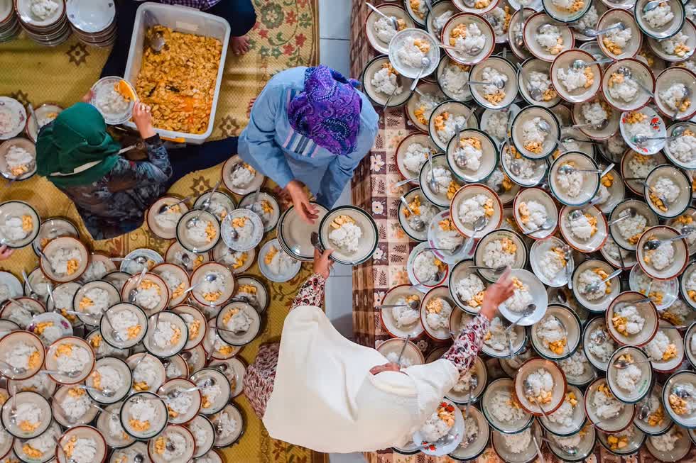   Ba người phụ nữ tình nguyện viên tham gia phục vụ 1.000 đĩa cơm gà chuẩn bị cho Iftar, một bữa ăn tối của người Hồi giáo để kết thúc lễ Ramadan vào lúc hoàng hôn. Ảnh: Dharma Kurniawan.  