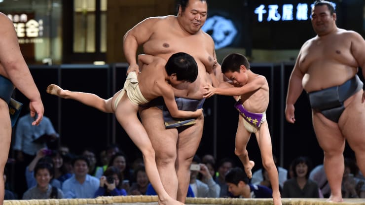Đô vật sumo chuyên nghiệp Toyonoshima nâng các đô vật sumo thiếu nhi trong một lễ thi đấu ở Tokyo.
