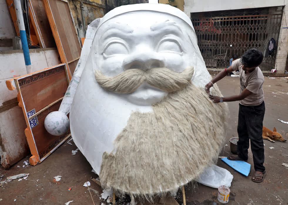 Một nghệ nhân chuẩn bị một khuôn mặt ông già Noel khổng lồ trước dịp lễ kỷ niệm Giáng sinh ở Kolkata, Ấn Độ, vào ngày 12/12. Ảnh: Reuters