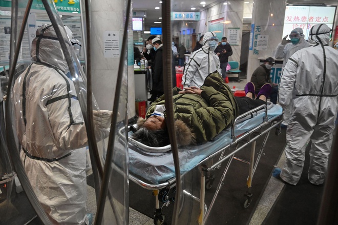 Nhân viên y tế mang đồ bảo hộ đưa một bệnh nhân nhiễm virus corona vào bệnh viện Chữ thập Đỏ thành phố Vũ Hán hôm 25/1. Ảnh: AFP.