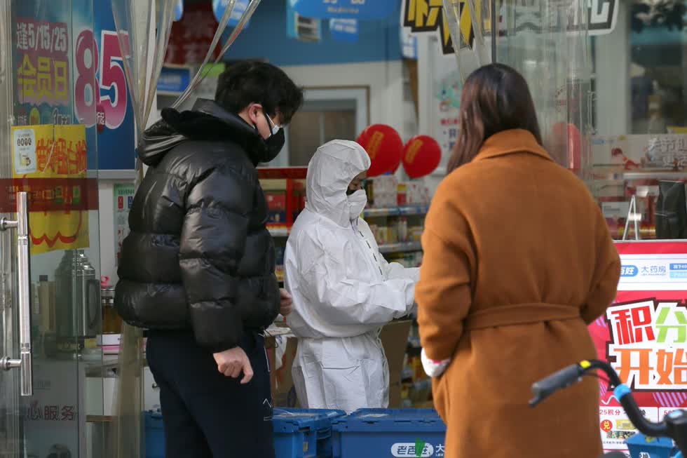 Một công nhân trong bộ đồ bảo hộ đã phục vụ khách hàng tại một hiệu thuốc ở Vũ Hán. Ảnh: REUTERS