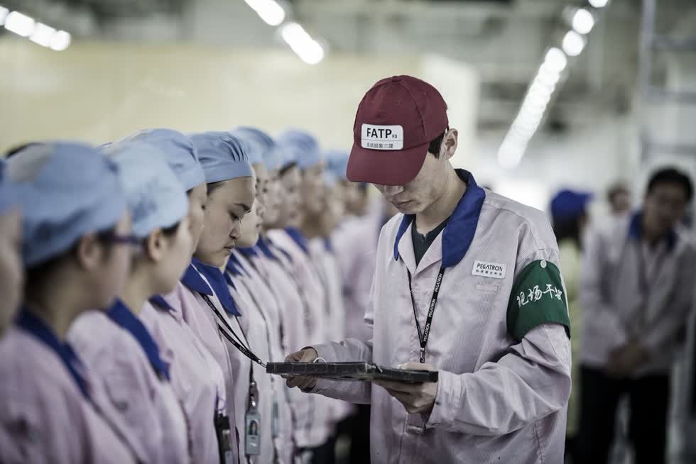 Một giám sát viên kiểm tra thẻ đeo của nhân viên tại nhà máy của Pegatron ở Thượng Hải. Ảnh: Bloomberg.