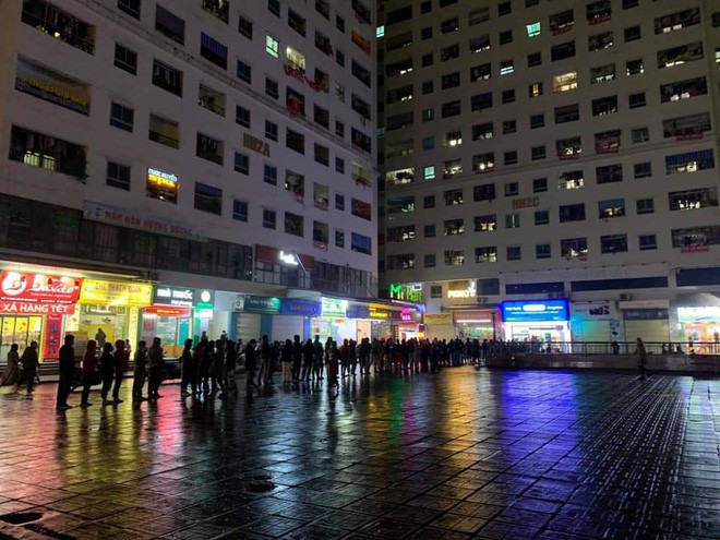 Nhiều cư dân sinh tại một khu chung cư ở Hà Nội đã kiên nhẫn xếp hàng dài đến gần nửa đêm mưa lạnh để mua khẩu.
