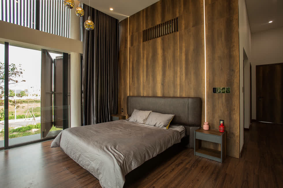 Căn phòng trang trí tối giản, nổi bật với bức tường ốp gạch giả gỗ ton-sur-ton với màu nội thất chung.