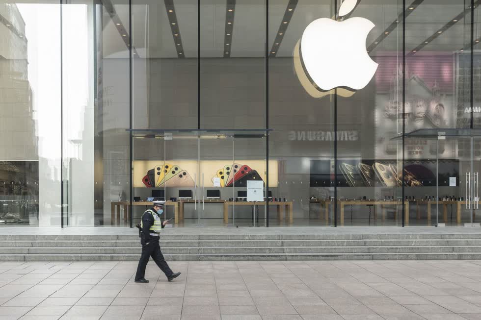   Một sĩ quan cảnh sát đeo mặt nạ bảo vệ đi ngang qua một cửa hàng Apple đã đóng cửa ở Thượng Hải vào ngày 5/2/2020. Ảnh: Bloomberg.  