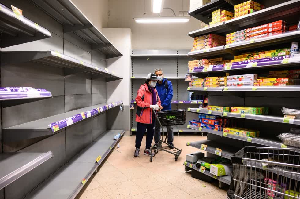 Những người mua sắm đeo khẩu trang bảo vệ đẩy xe của họ qua các kệ siêu thị với các kệ trống không tại Hồng Kông vào ngày 6/2/2020. Ảnh: Bloomberg.