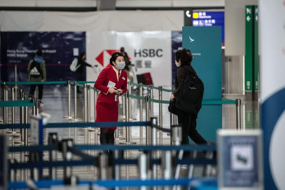  Một nhân viên của Cathay Pacific Airlines đeo khẩu trang nói chuyện với một hành khách tại sân bay quốc tế Hồng Kông vào ngày 6/2/2020. Ảnh: Bloomberg  