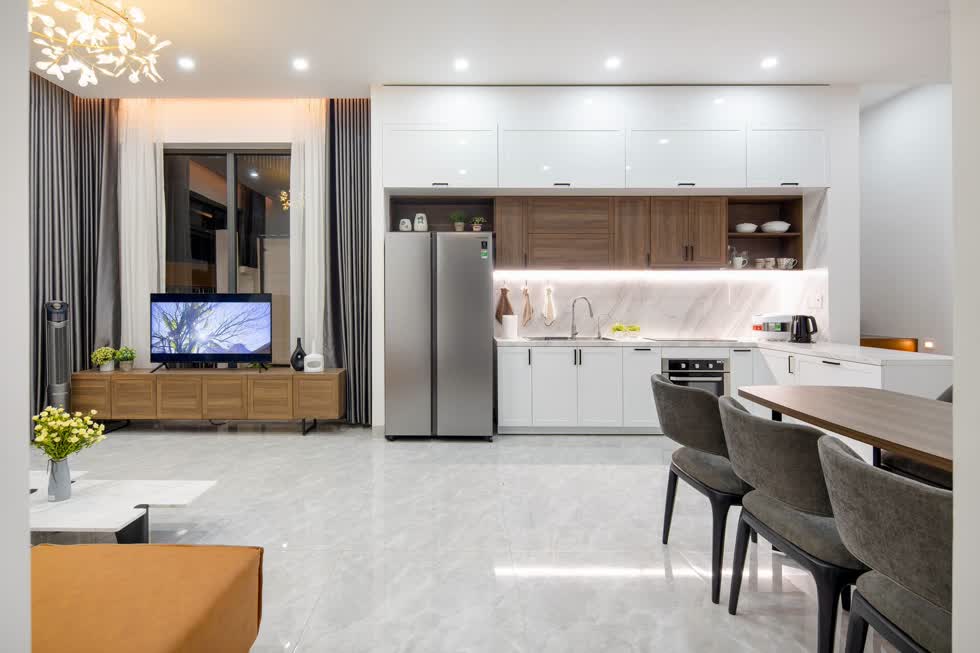 Tiếp nối với phòng khách là khu vực bếp - ăn. Để tối ưu diện tích sinh hoạt và để đồ, tủ bếp được đóng cao chạm trần cùng bếp được thiết kế chữ L rất tiện nghi.