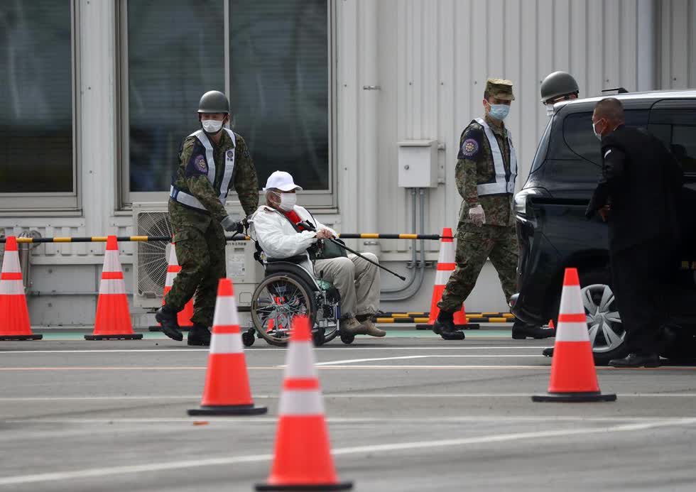 Một người đàn ông ngồi xe lăn được trợ giúp rời khỏi du thuyền Diamond Princess sáng 19/2. Ảnh: Reuters.