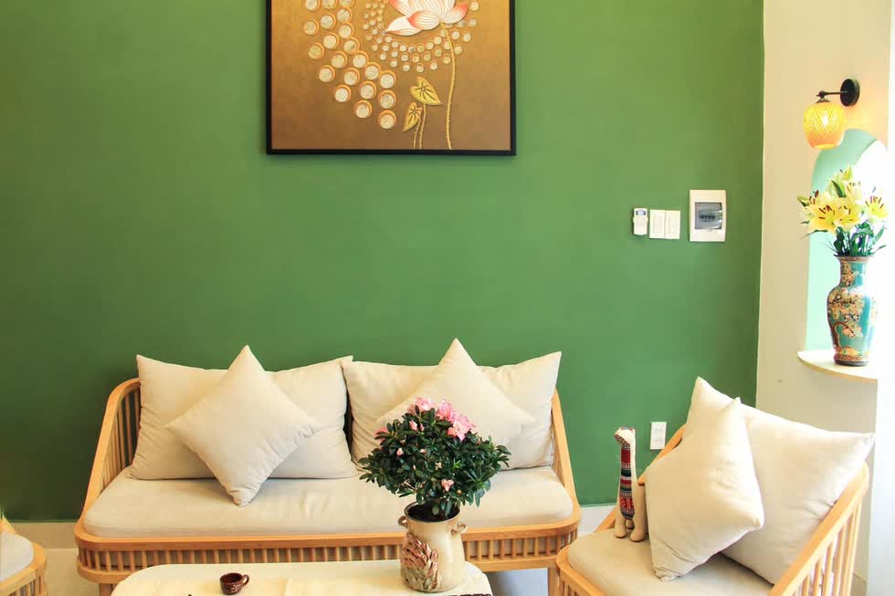 Không gian phòng khách nhẹ nhàng mà vẫn ấm cúng, bức tranh nghệ thuật được đặt trên nền tường xanh lá tạo điểm nhấn ấn tượng.