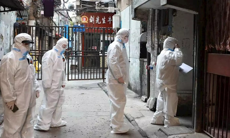 Nhân viên y tế mặc đồ bảo hộ đi kiểm tra từng ngôi nhà ở quận Giang Hán, thành phố Vũ Hán hôm 17/2. Ảnh: China Daily.
