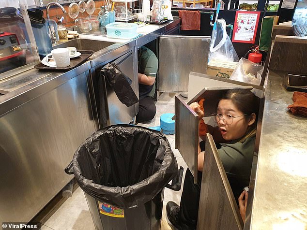Nhân viên cửa hàng cà phê trong trung tâm thương mại tìm chỗ nấp.