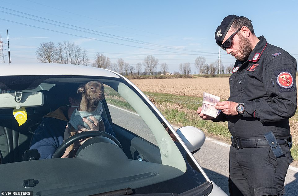   Một sĩ quan quân đội Italy kiểm tra các giấy phép của một người lái xe ô tô đi cùng chú chó của mình ở San Fiorano, với các nhà chức trách hôm nay áp đặt các trạm kiểm soát để thực thi một kiểm dịch mới quyết liệt.  