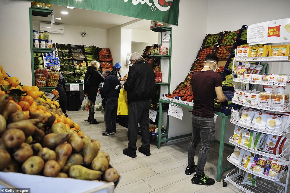   Mọi người xếp hàng bên trong một cửa hàng rau quả đứng cách nhau ít nhất một mét trong một thị trấn bán hoang ở Viareggio, Ý, hôm nay (12/3).  