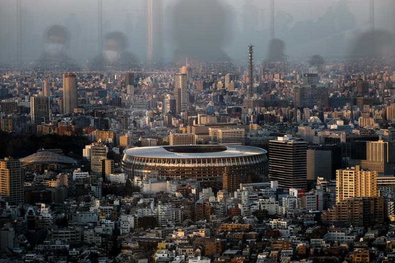   Sân vận động quốc gia Olympic mới và những người đeo khẩu trang bảo vệ được phản chiếu tại tầng quan sát bầu trời Shibuya, sau khi một đợt bùng phát do virus corona ở Tokyo, Nhật Bản.  