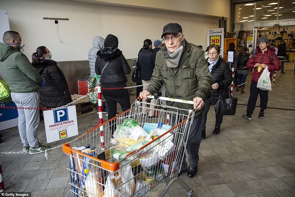   Một người đàn ông lớn tuổi với một giỏ hàng đầy đủ gần một siêu thị ngày nay ở Naples. Nhiều cửa hàng thấy hoảng loạn khi khách mua hàng và xếp hàng dài.  
