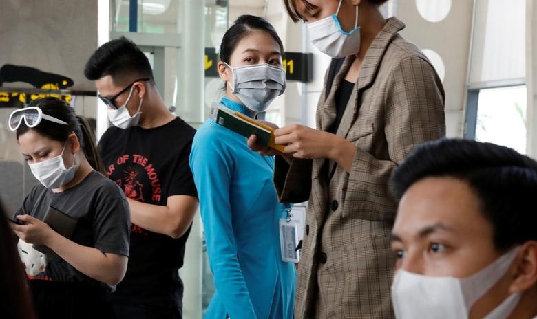   Một nhân viên mặt đất của Vietnam Airlines và hành khách đeo khẩu trang bảo vệ đang chờ lên máy bay tại sân bay Đà Nẵng ở thành phố Đà Nẵng, Việt Nam ngày 23/2.   