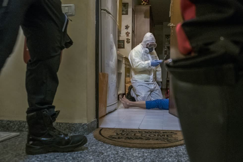 Một nhân viên y tế đang tuần tra với cảnh sát ở Milan để kiểm tra thân nhiệt của một người vào ngày 11/4. Ảnh: Bloomberg