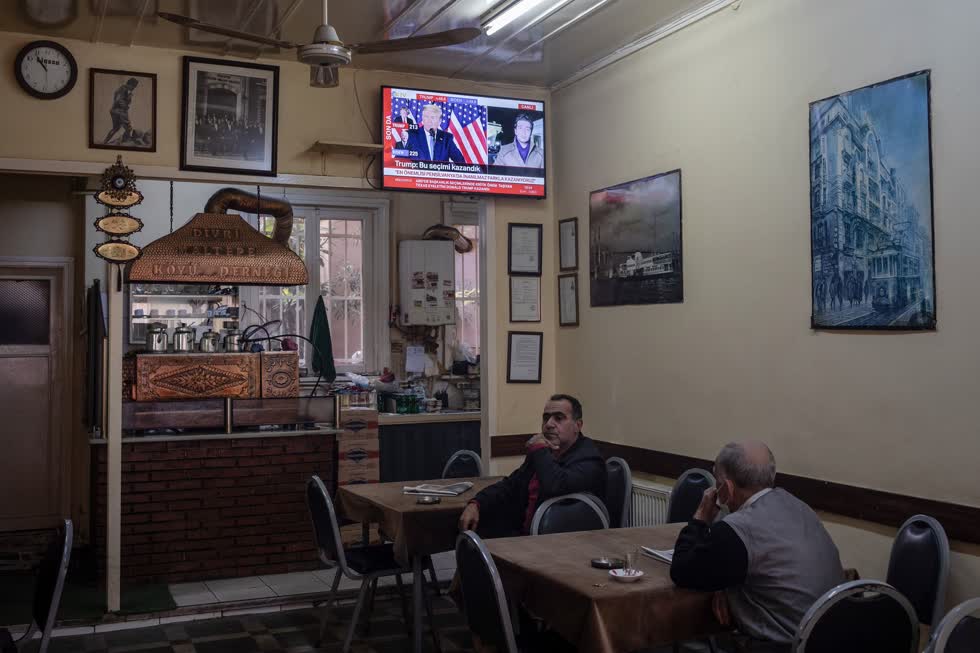  Khách hàng tại một quán trà ở Istanbul xem chương trình phát sóng trực tiếp cuộc họp báo của ông Trump vào ngày 4/11, (ảnh trái). Một đội vệ sinh dọn dẹp bàn làm việc tại Nghị viện Châu Âu ở Brussels vào ngày 8/7 (ảnh phải). Ảnh: Bloomberg