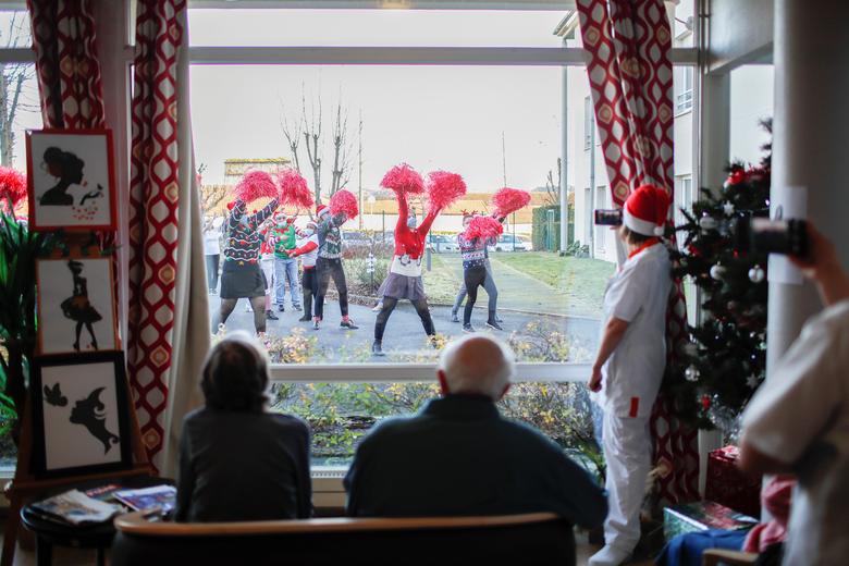 Người dân xem các nhân viên y tế biểu diễn qua cửa sổ trong bữa tiệc Giáng sinh tại cơ sở giành cho người già ở Pháp, ngày 18/12. Nguồn ảnh: Reuters