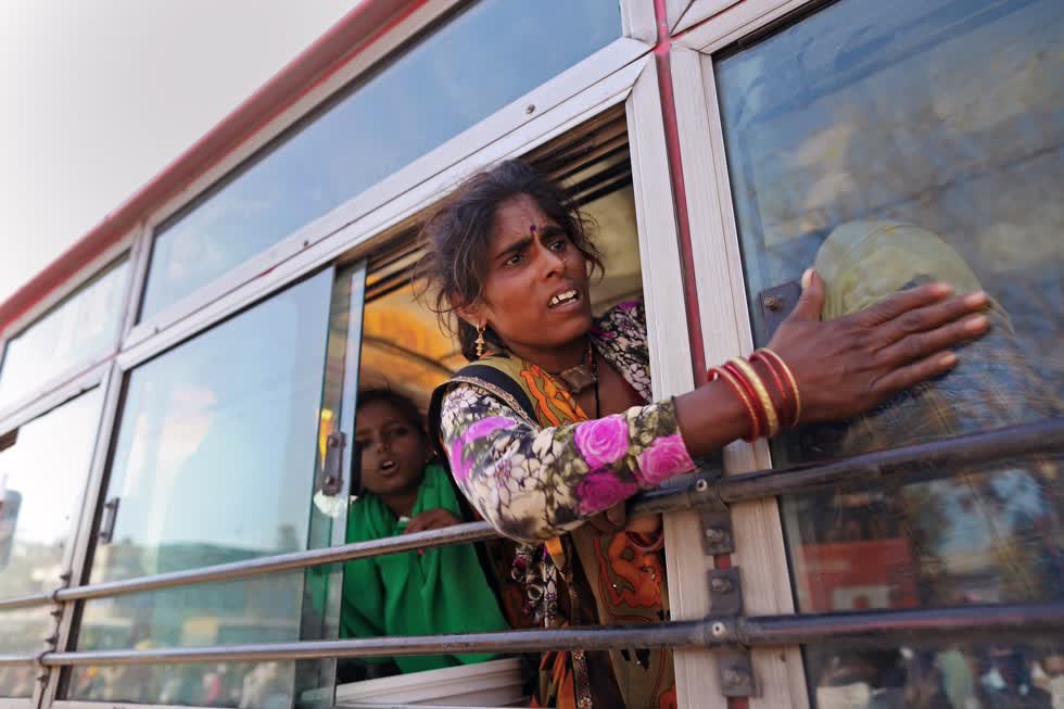 Một công nhân nhập cư hét lên với con cô ấy từ một chiếc xe buýt ở ngoại ô New Delhi vào ngày 29/3, trong thời gian Ấn Độ đóng cửa. Hàng triệu người lao động buộc phải trở về quê hương và làng mạc khi việc làm ở các thành phố không còn. Ảnh: Bloomberg