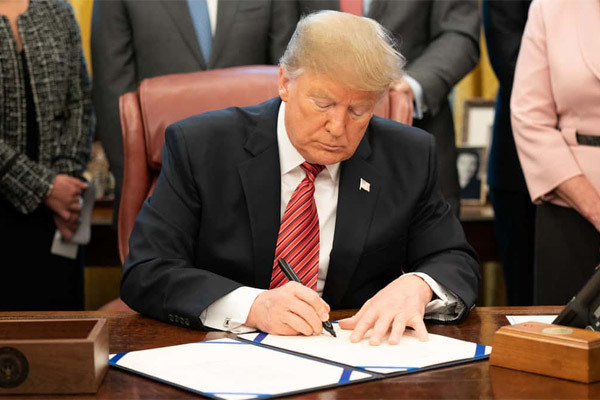 Tổng thống Donald Trump ký thông qua luật mới cho phép loại bỏ các công ty Trung Quốc ra khỏi sàn chứng khoán Mỹ. Ảnh: AP