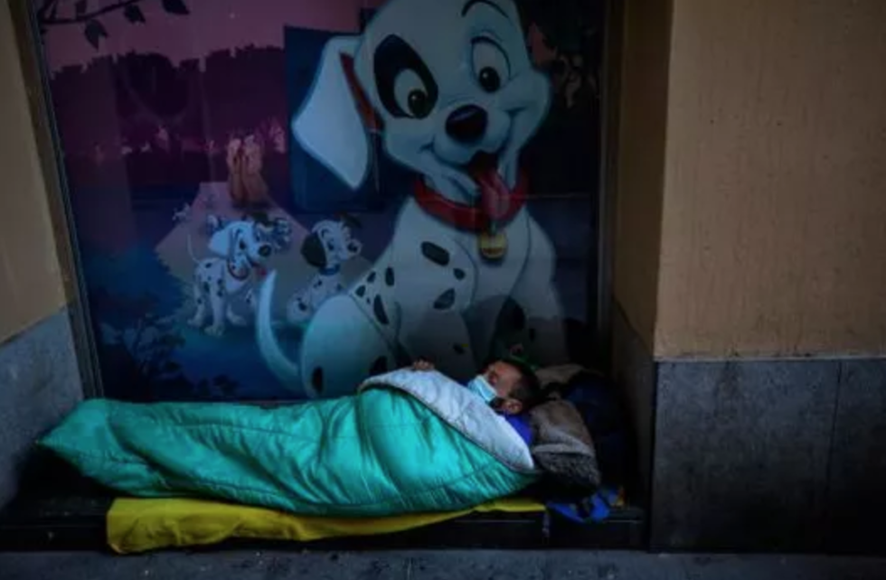 Một người đàn ông vô gia cư đeo mặt nạ ngủ ở ngưỡng cửa của một tòa nhà, ở Barcelona, ​​Tây Ban Nha. Ảnh: AP