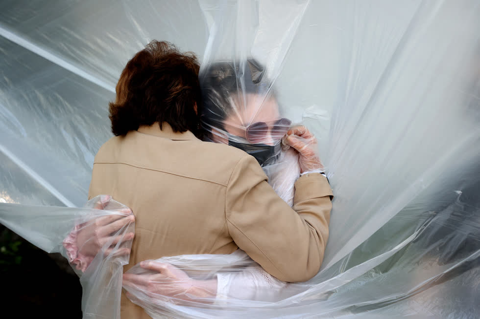Wantagh, N.Y., ngày 24/5/2020. Olivia Grant ôm bà ngoại của mình, Mary Grace Sileo, qua một miếng vải nhựa treo trên dây phơi. Đây là lần liên lạc đầu tiên của họ kể từ khi bắt đầu khóa cửa do đại dịch gây ra. Ảnh: Al Bello / Getty