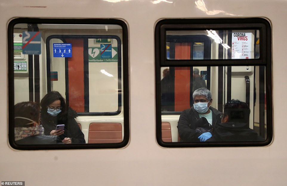  Một người phụ nữ nhận khẩu trang từ cảnh sát thành phố tại một ga tàu điện ngầm ở Madrid (ảnh phải), cũng như ngồi ở một khoảng cách trên tàu điện ngầm Madrid.